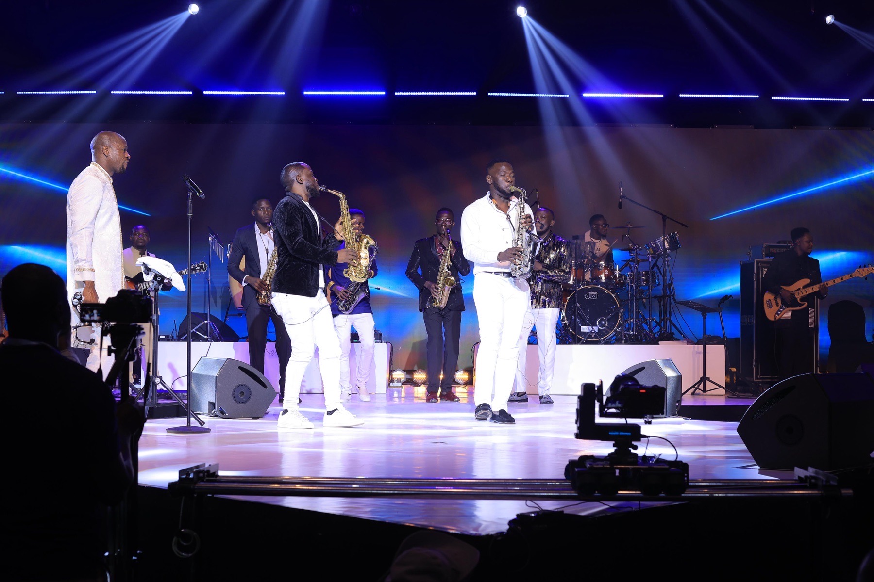 Live band and saxophonists performing beneath blue spotlights