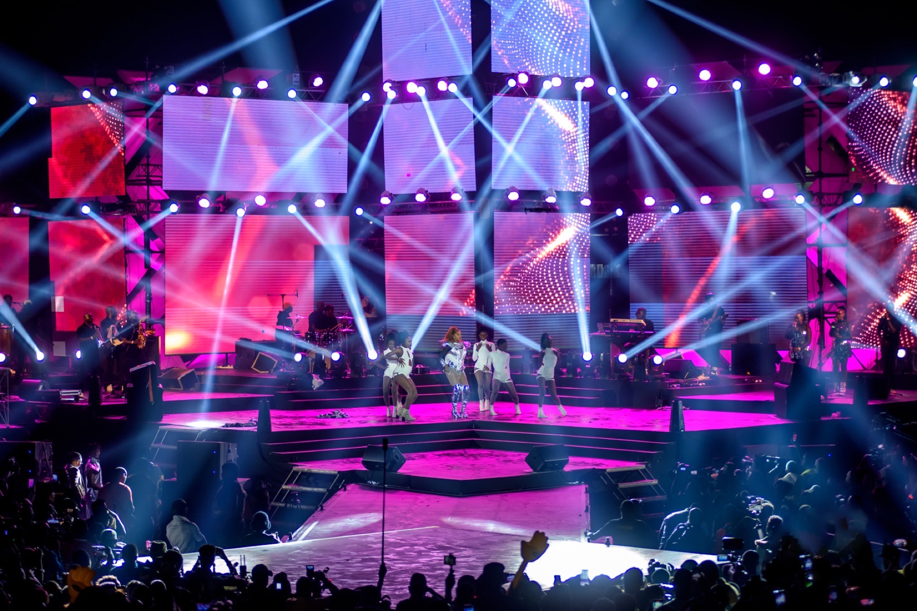 Wide view of a runway concert stage filled with performers and lights