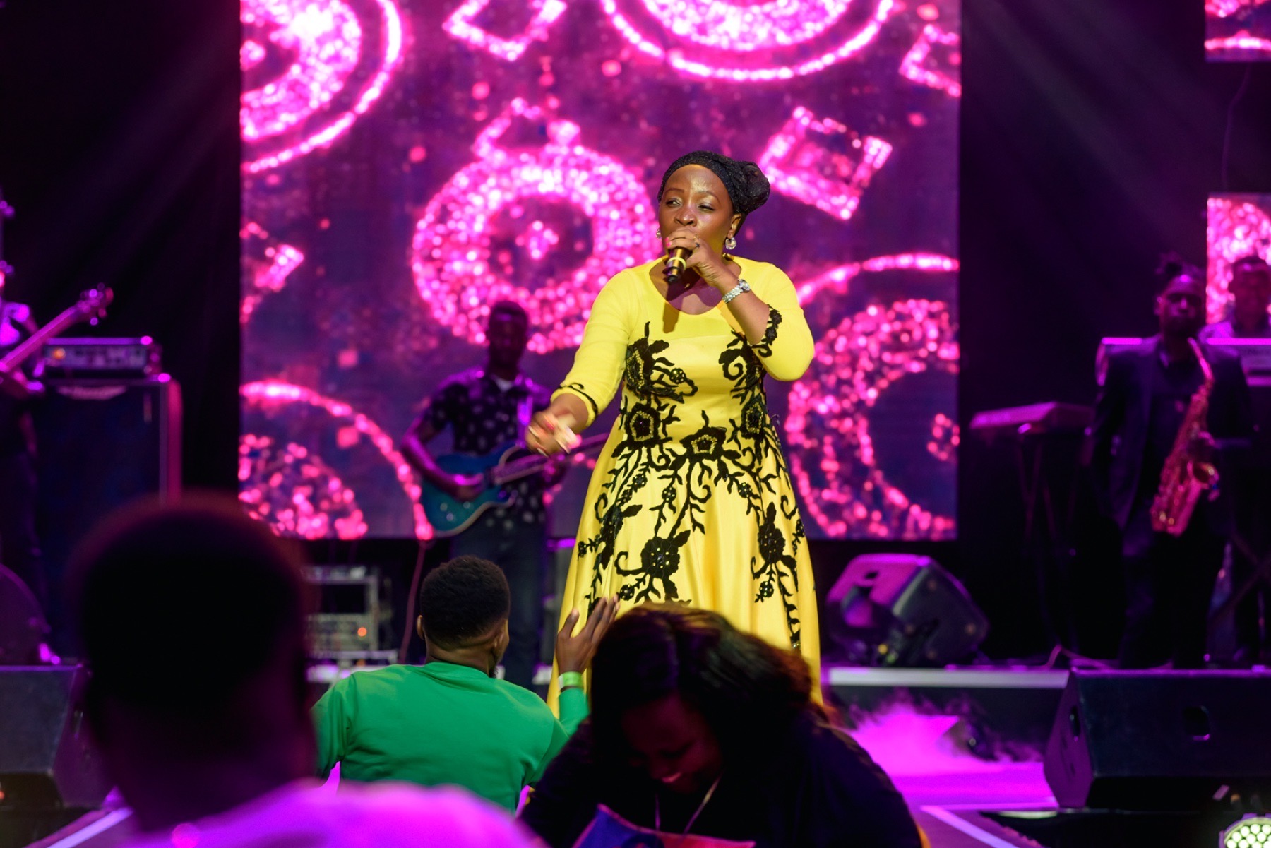 Singer in a yellow dress performing on a concert stage