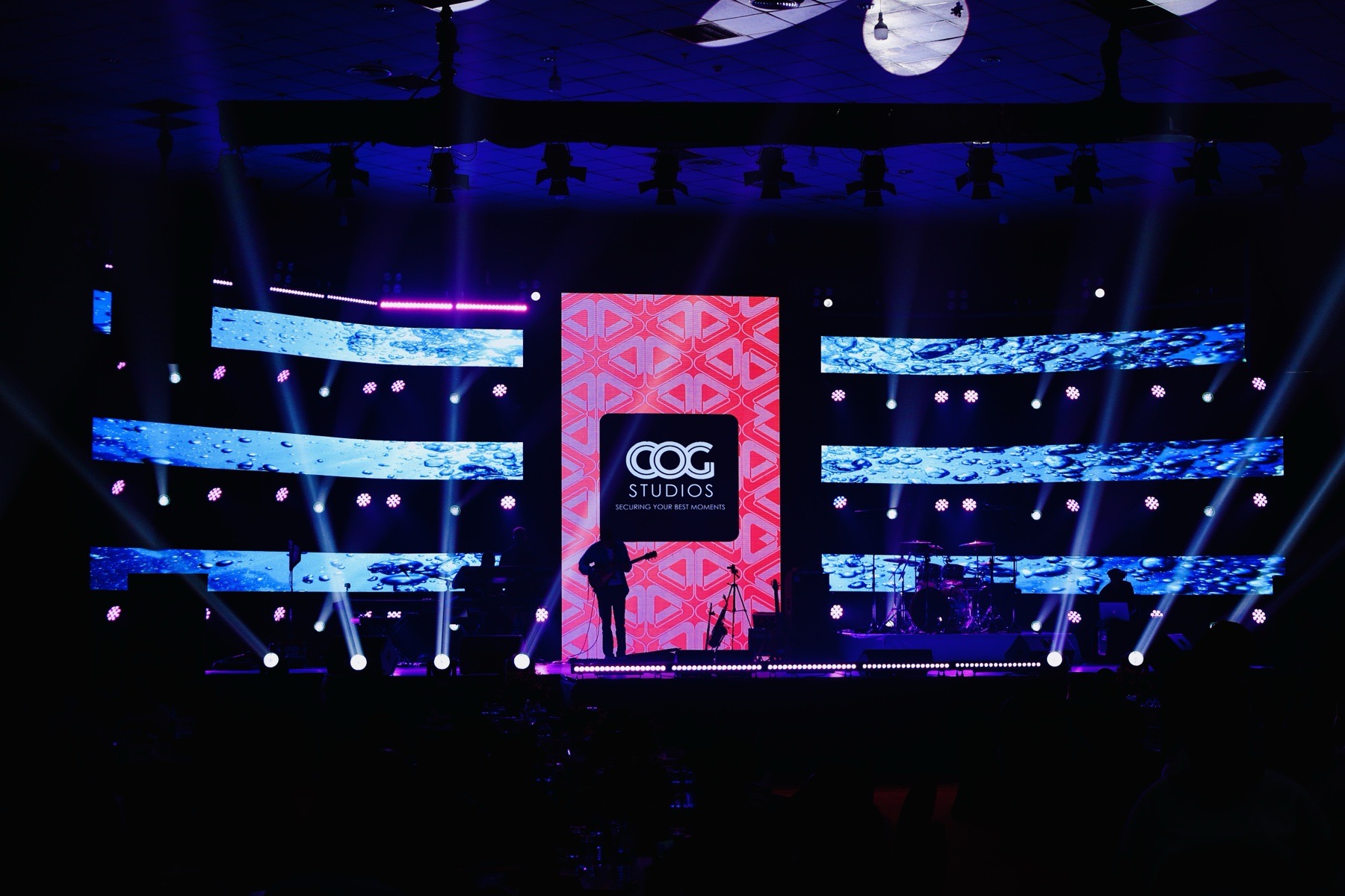 Large event stage illuminated with LED screens and COG Studios branding