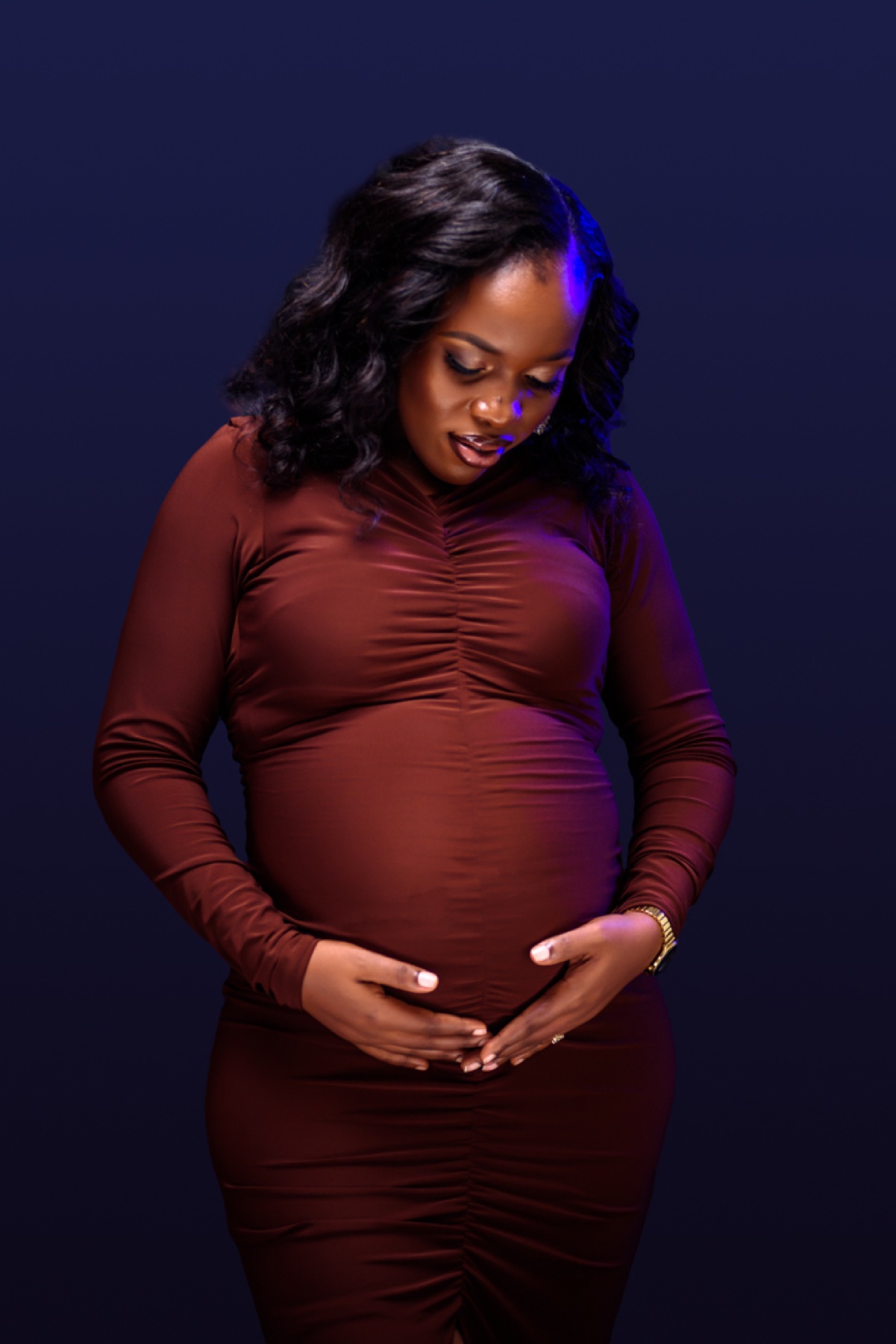 Expectant mother in a burgundy dress for a maternity portrait